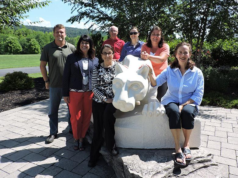 教师 and 工作人员 members posing with the nittany lion shrine